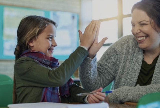 Una maestra ayudando con alegria y amor motivando a seguir con sus actividades de buena manera 